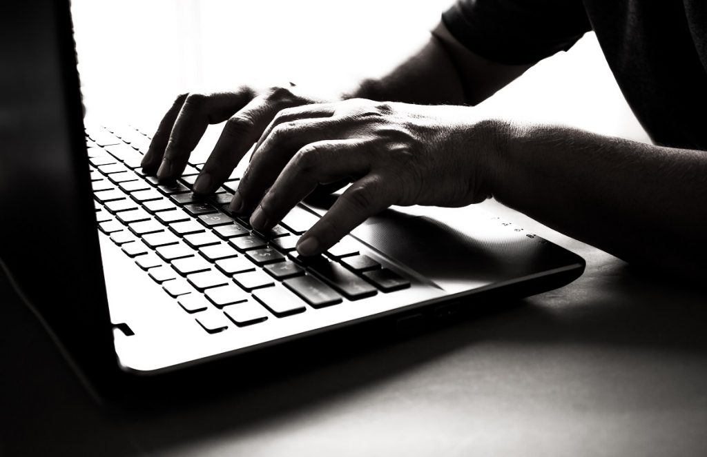 man typing on a laptop